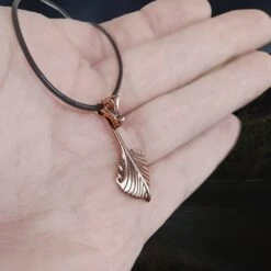 Oseberg Bronze Viking Ship Pendant -The Viking Dragon Shop wl bronze oseberg viking ship pendant on leather thong on hand side angle view